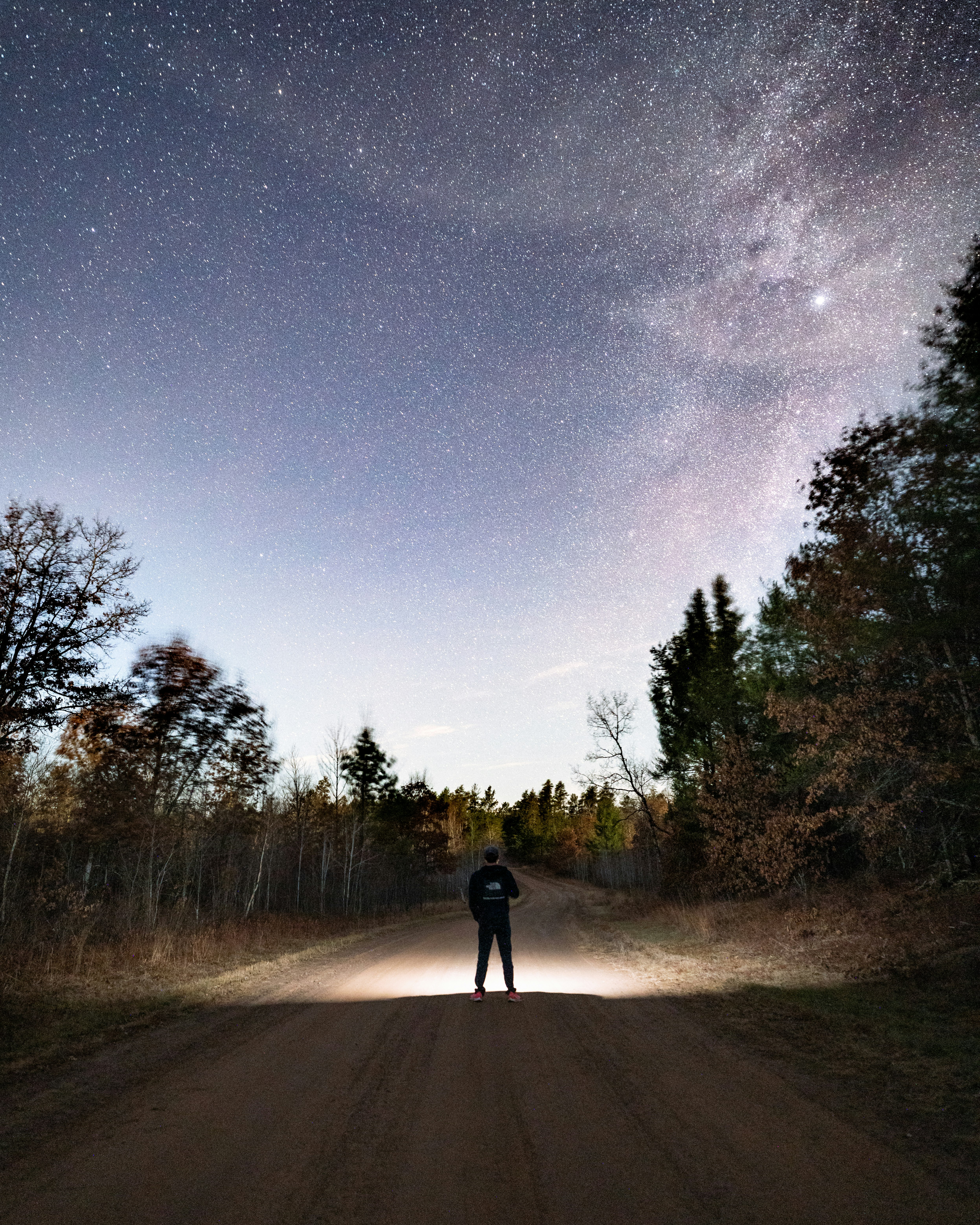 person in black jacket standing on road during night time